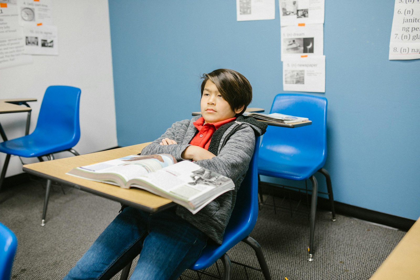 A solitary young student sitting alone in a classroom, appearing thoughtful.