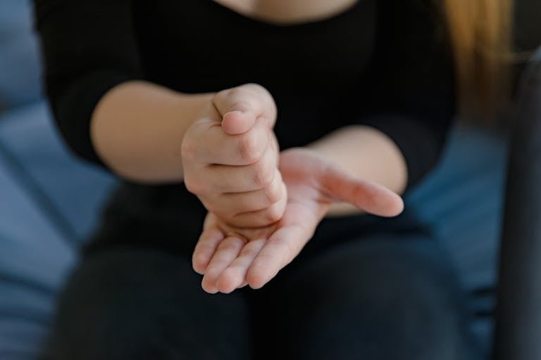 Close-up shot of a woman using sign language indoors, emphasizing communication.