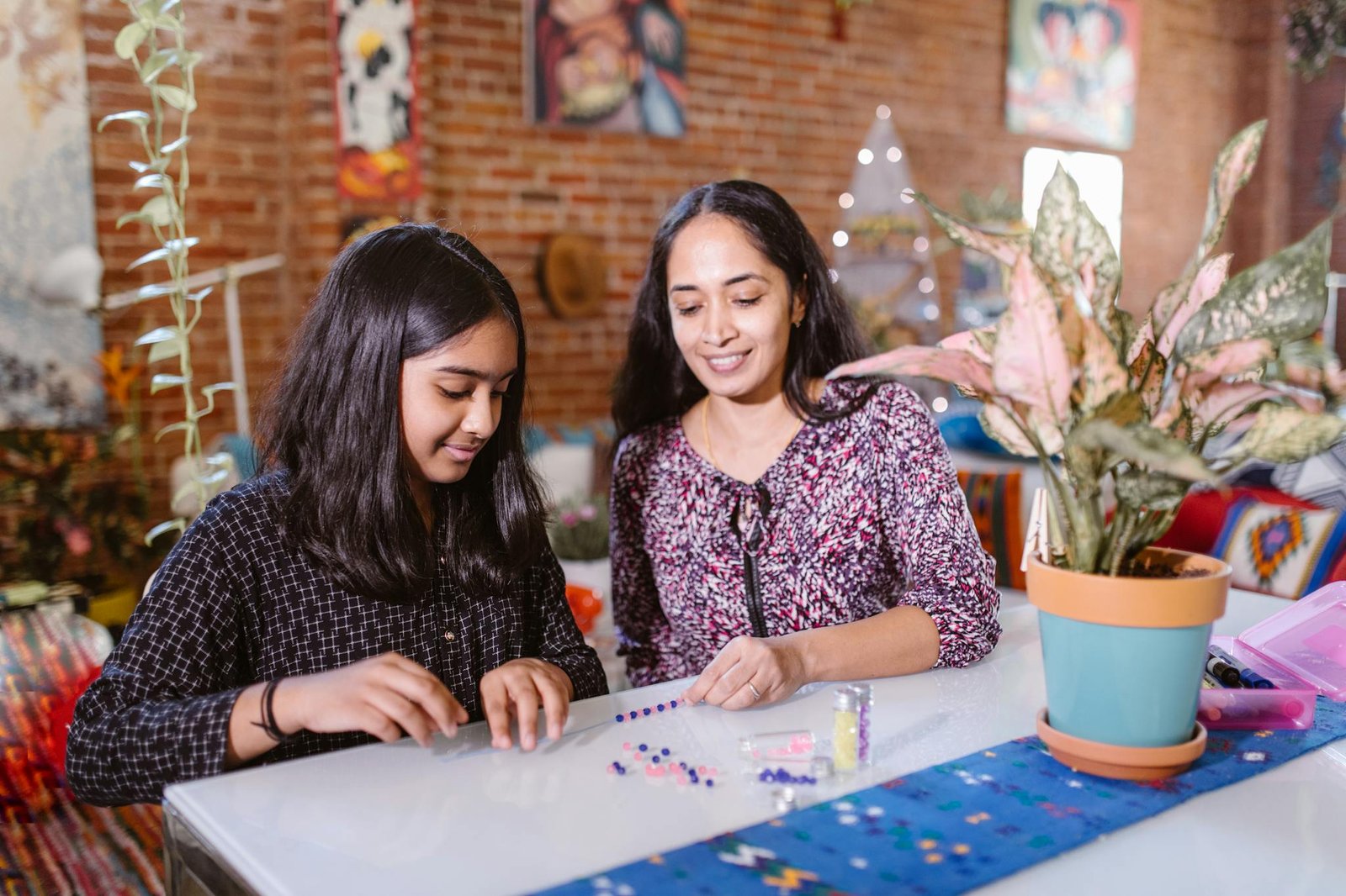 Mother and daughter creating a colorful beaded bracelet together at home.