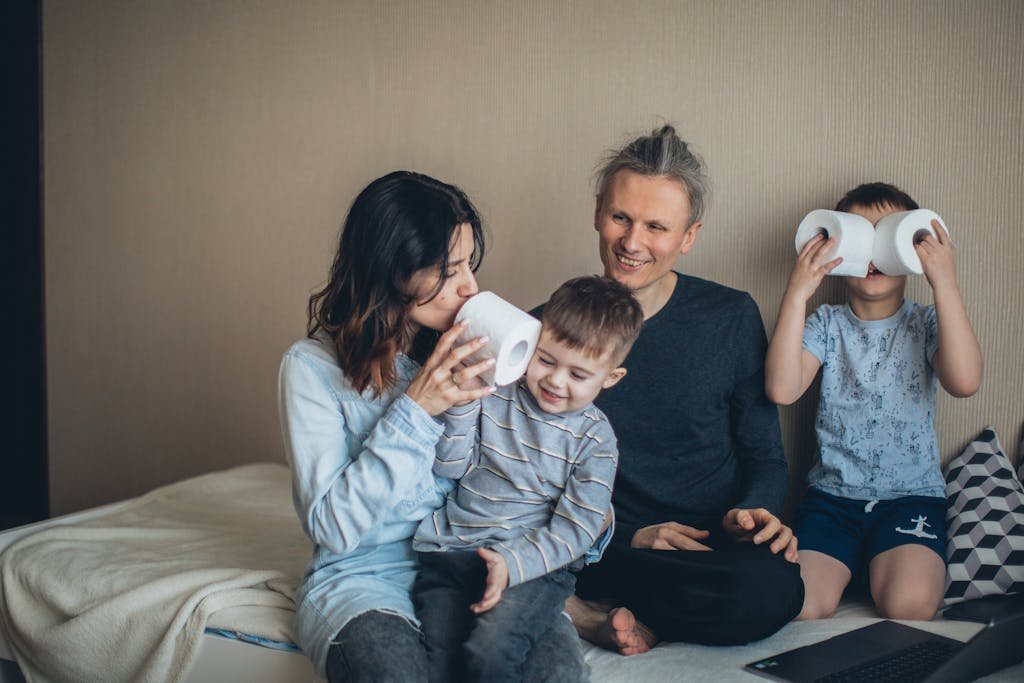 Family enjoying playful bonding time together indoors. Parent and kids having fun with toilet paper rolls.
